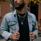 Men's 7mm stainless steel Figaro chain necklace styled against soft fabric  