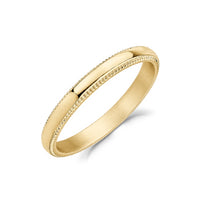 Gold stainless steel 3mm domed milgrain wedding band photographed at an angle showing the beaded edge texture and smooth polished dome.