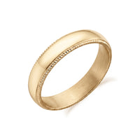 Stainless steel wedding band resting on a white surface, emphasizing its reflective finish and milgrain texture.  