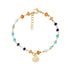 Gold beaded bracelet with turquoise, lapis, and coral beads and a small seashell charm on white background