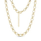 Close-up of structured link necklace in gleaming gold stainless steel with oval and cross-shaped links, showing lobster clasp and extension chain