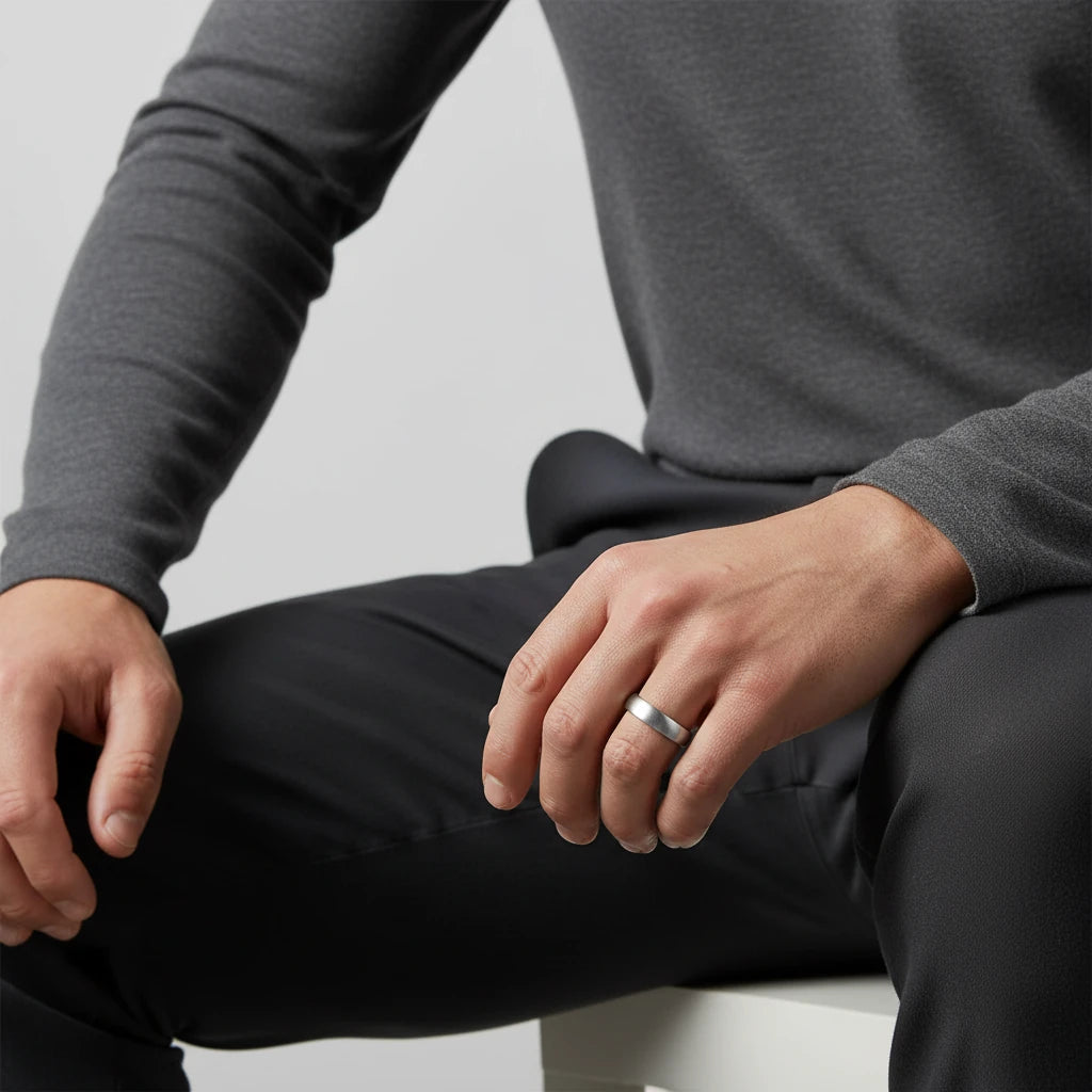 A man wearing a 4mm stainless steel comfort fit ring on his left hand, showcasing the product in a natural, relaxed pose with soft studio lighting.